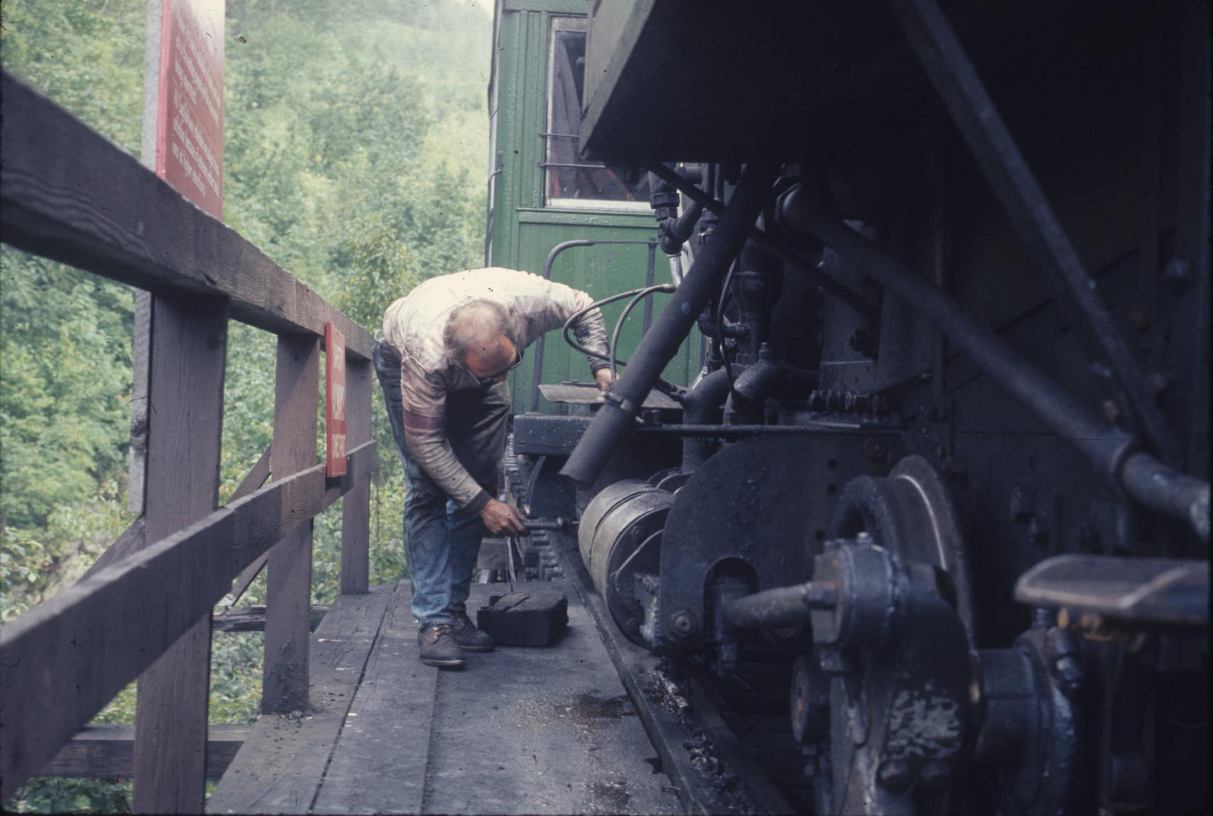 Engine tender greasing undercarriage at Base station