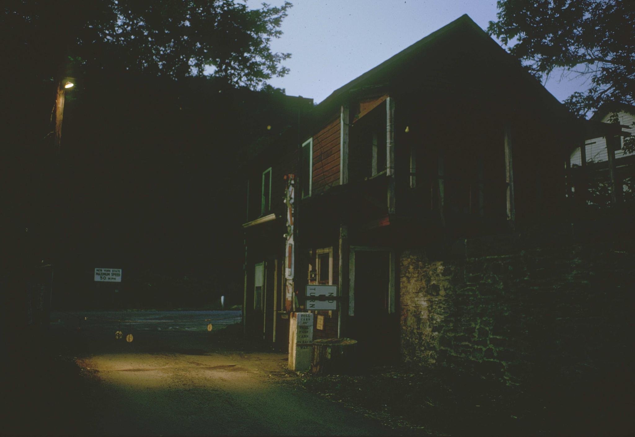 Photograph of toll house on New York side of Delaware Aqueduct at dusk.The…