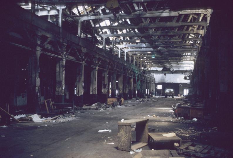 Interior view down center bay of abandoned mill building showing bridge cranes…