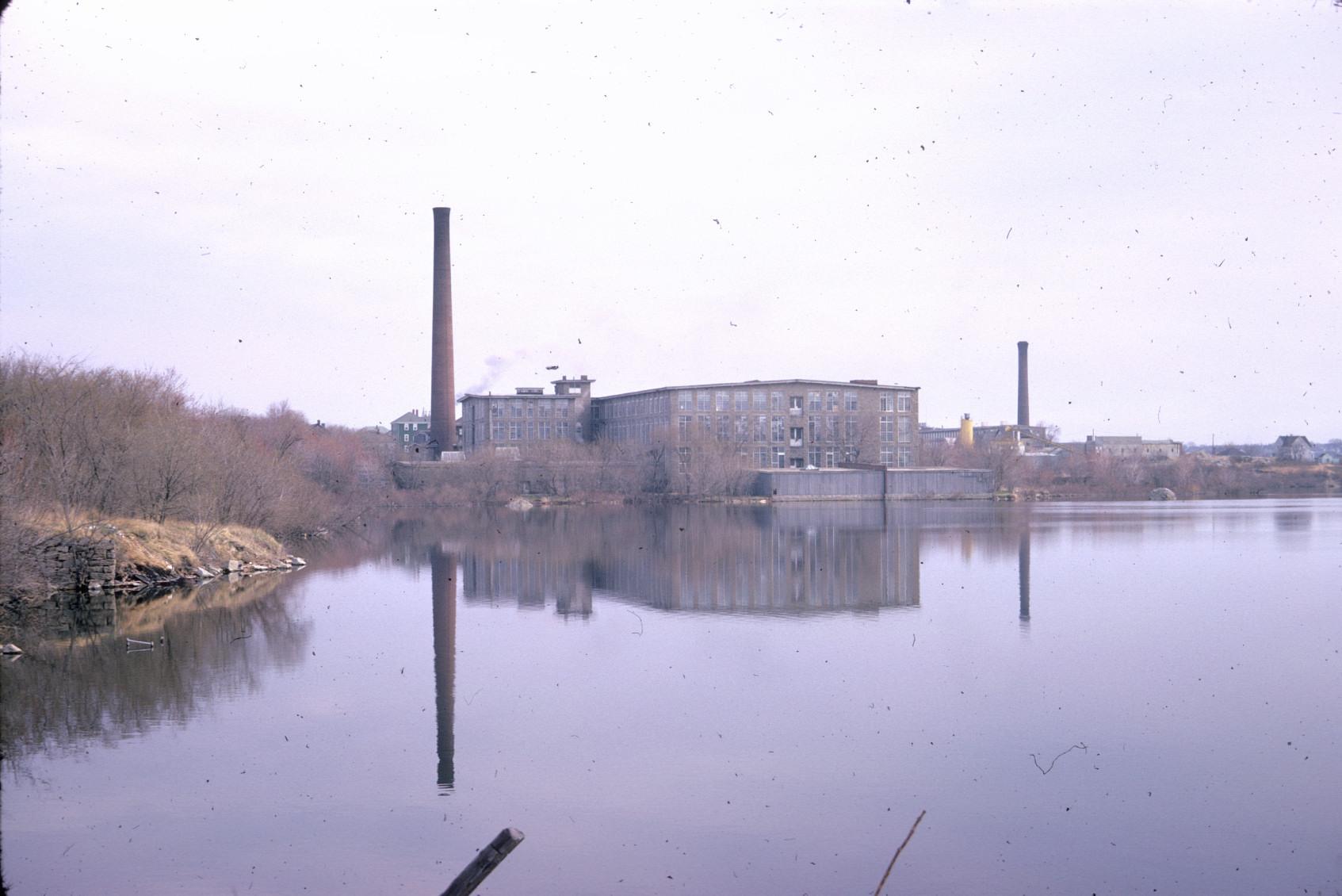 Distant view of the Charlton Mill from across Laurel Lake in Fall River.  Note…