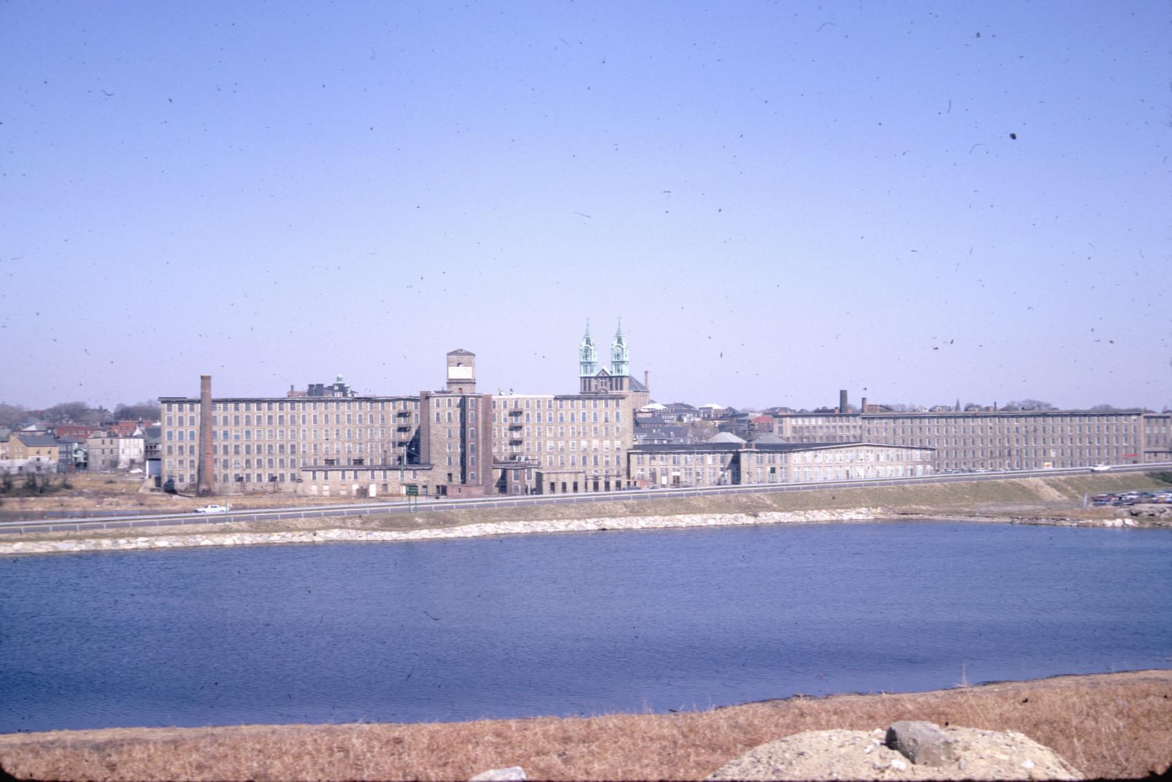 View of Barnard Mill from across the Quequechan River.  Note church in…