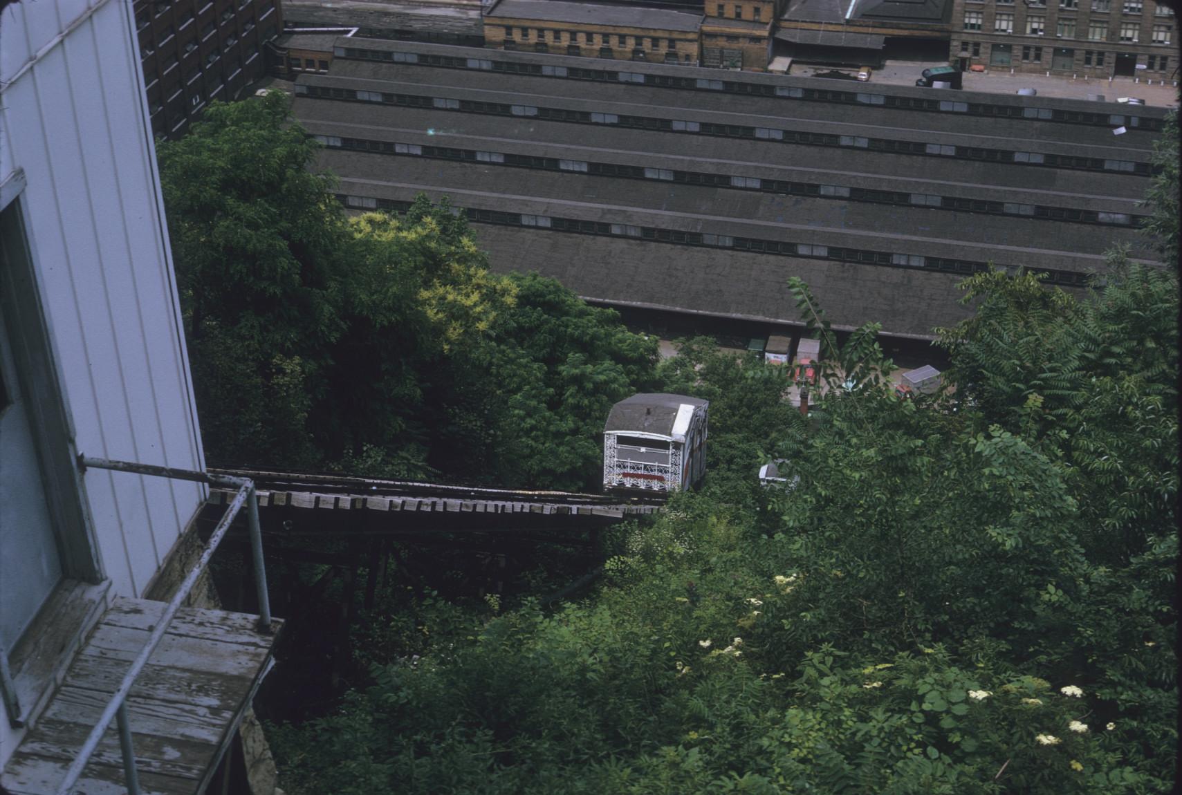 Side view down incline plane with car at mid-slope, Station Square in background