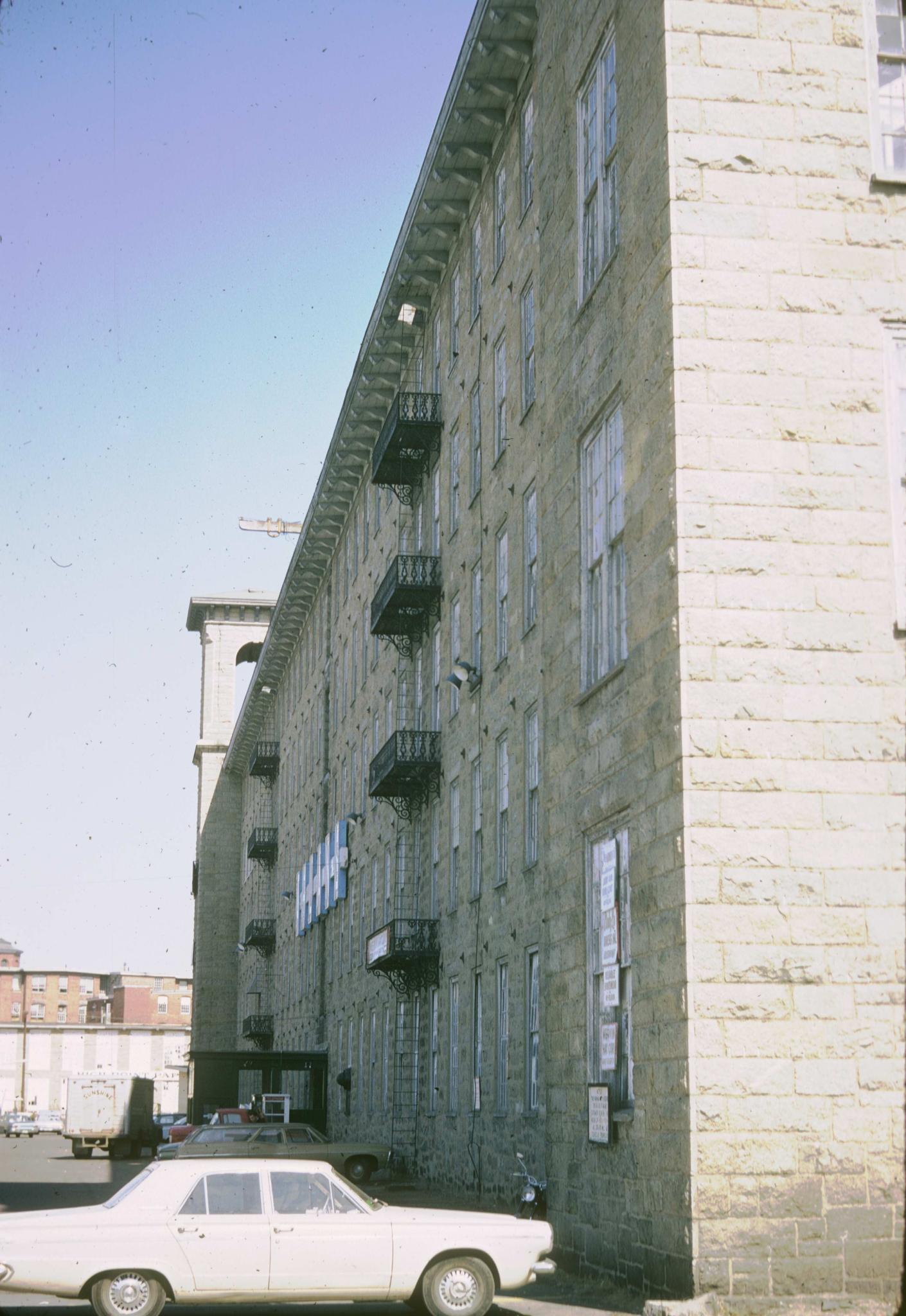 Photograph of the elevation of the mill showing wrought iron fire-escape.  Cars…