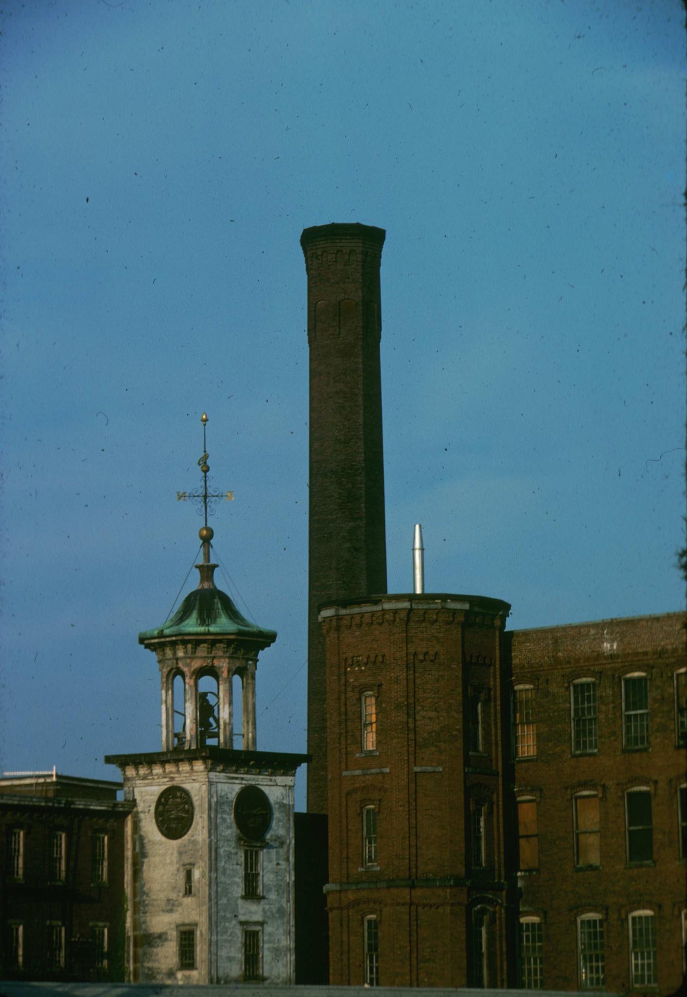 Photograph of the Boott mill showing the towers and smokestack.  Original…