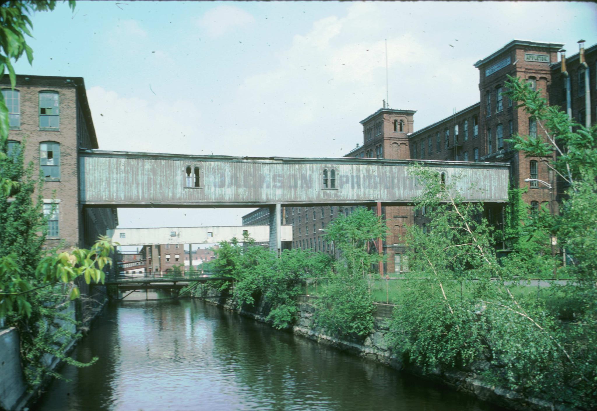 Photograph of the Appleton Mill showing two enclosed bridges passing over a…