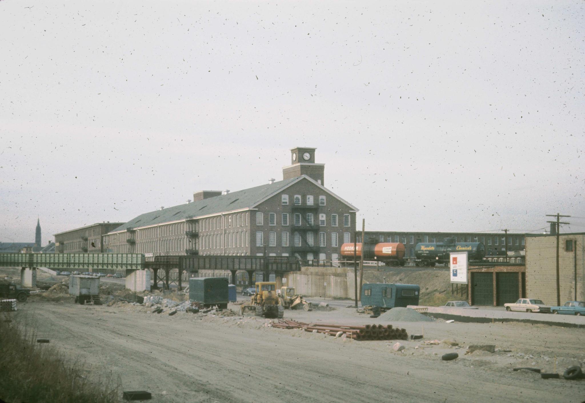 Photograph of the mill.  A railroad passes through the foreground.