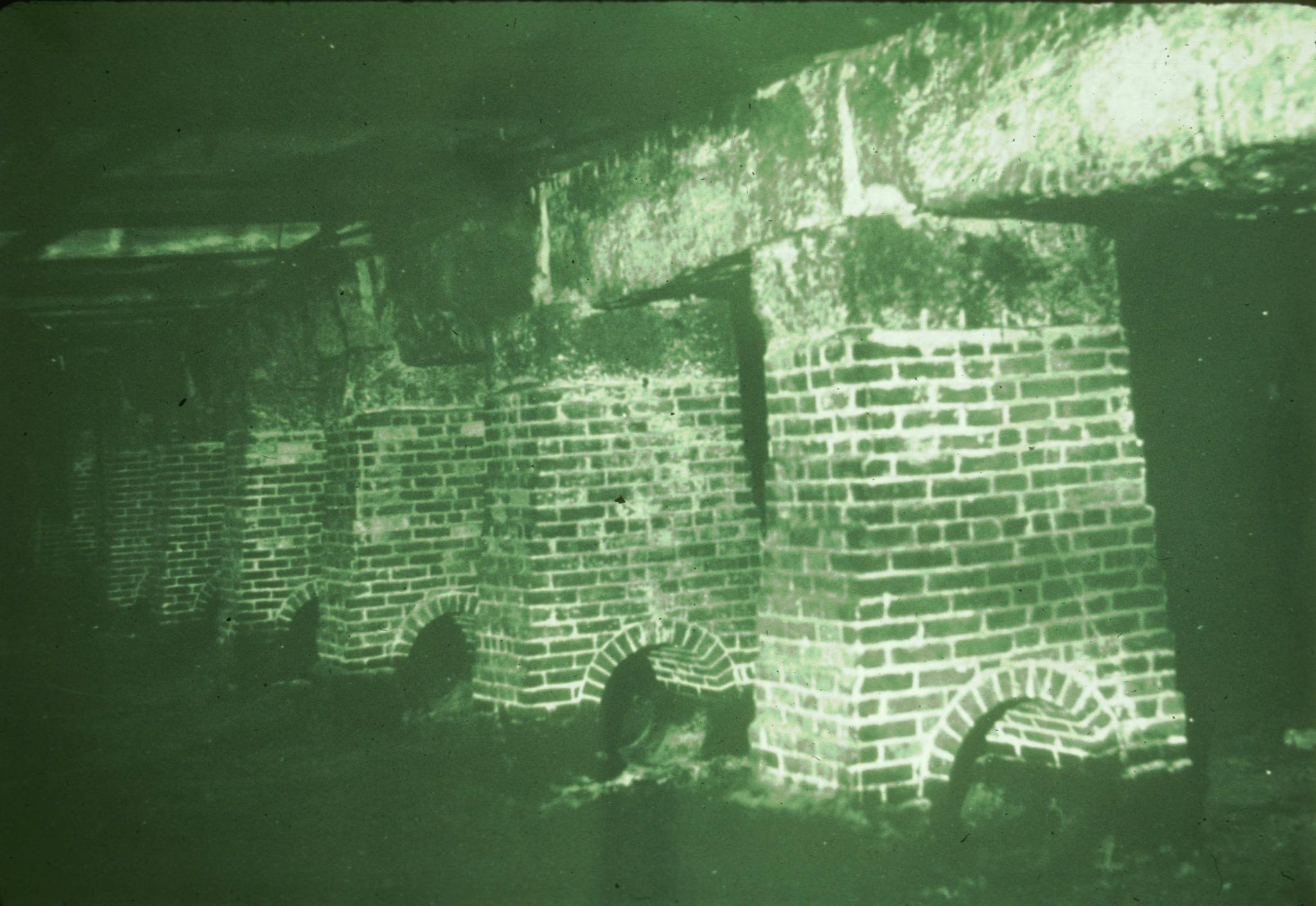 Photograph of brick piers and granite beams in the basement of the mill.