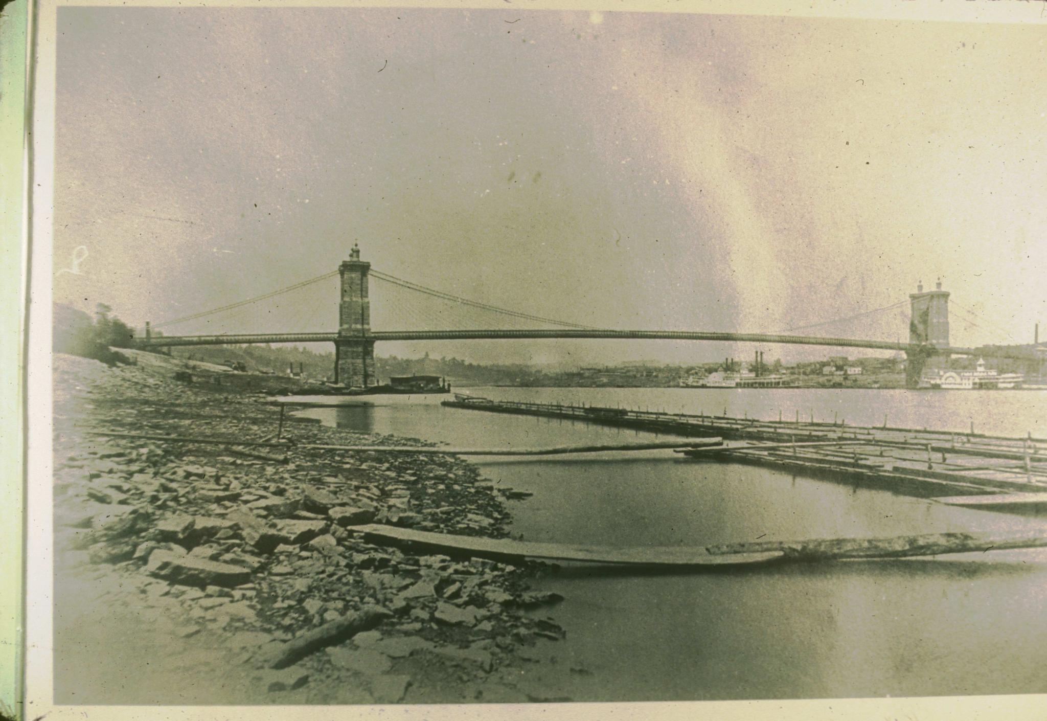 Historic photograph of the Cincinnati Bridge circa 1868.  Two steamships are…