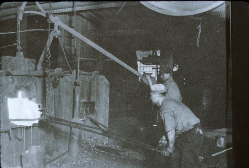 Reproduction of B&W photograph showing mass of iron being manipulated in…