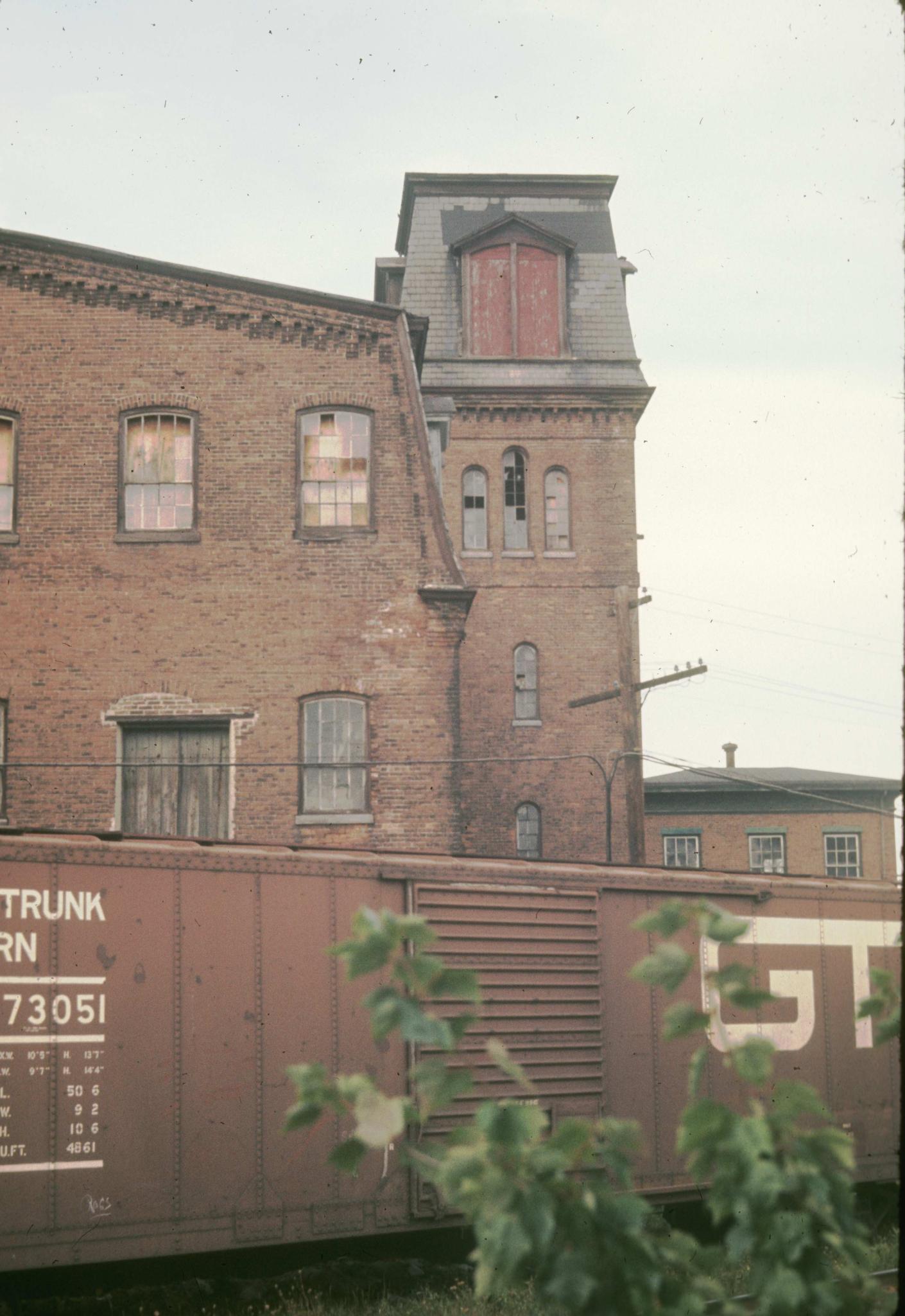 Photograph of side of the mill with a railroad boxcar in the foreground.