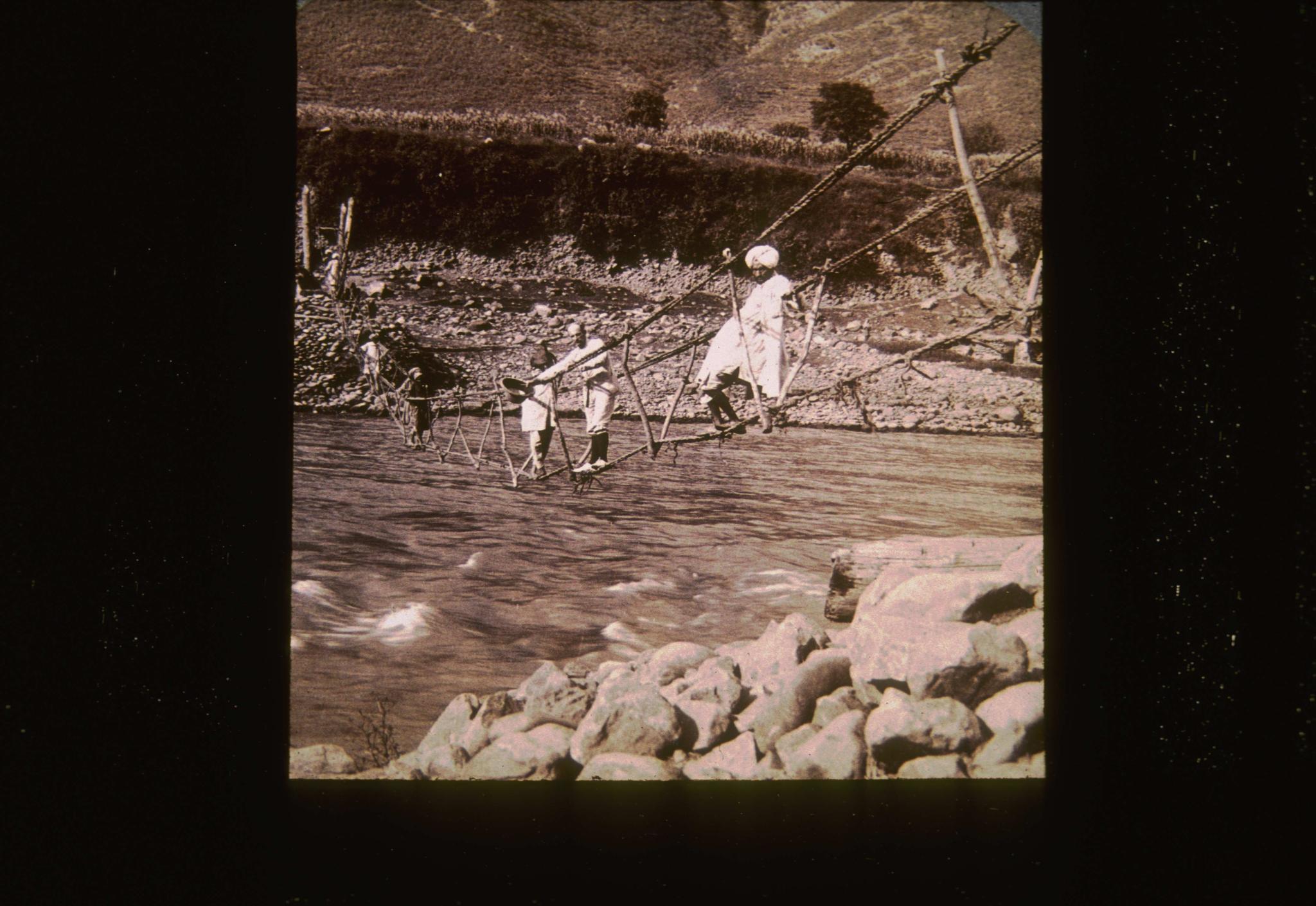 Unidentified primitive suspension bridge at an unidentified location.  Bridge…