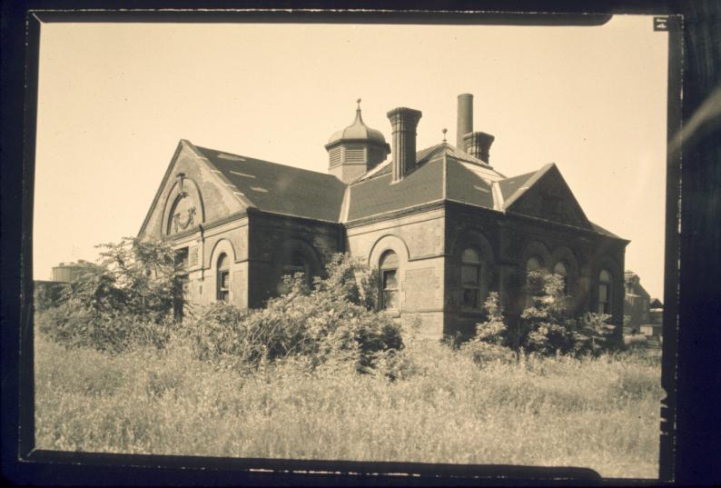 View of overgrown office building, structure noted to be "ca. 1886."