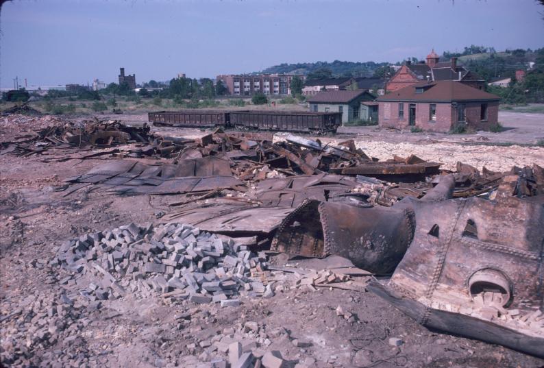 View of scrap metal, rail cars, office building, and masonry rubble during…