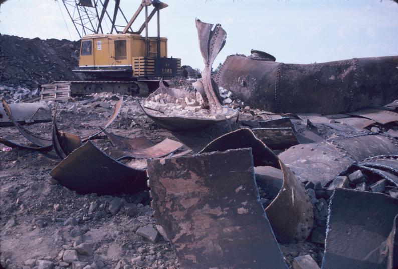 View of scrap metal and large crane during blast furnace demolition.