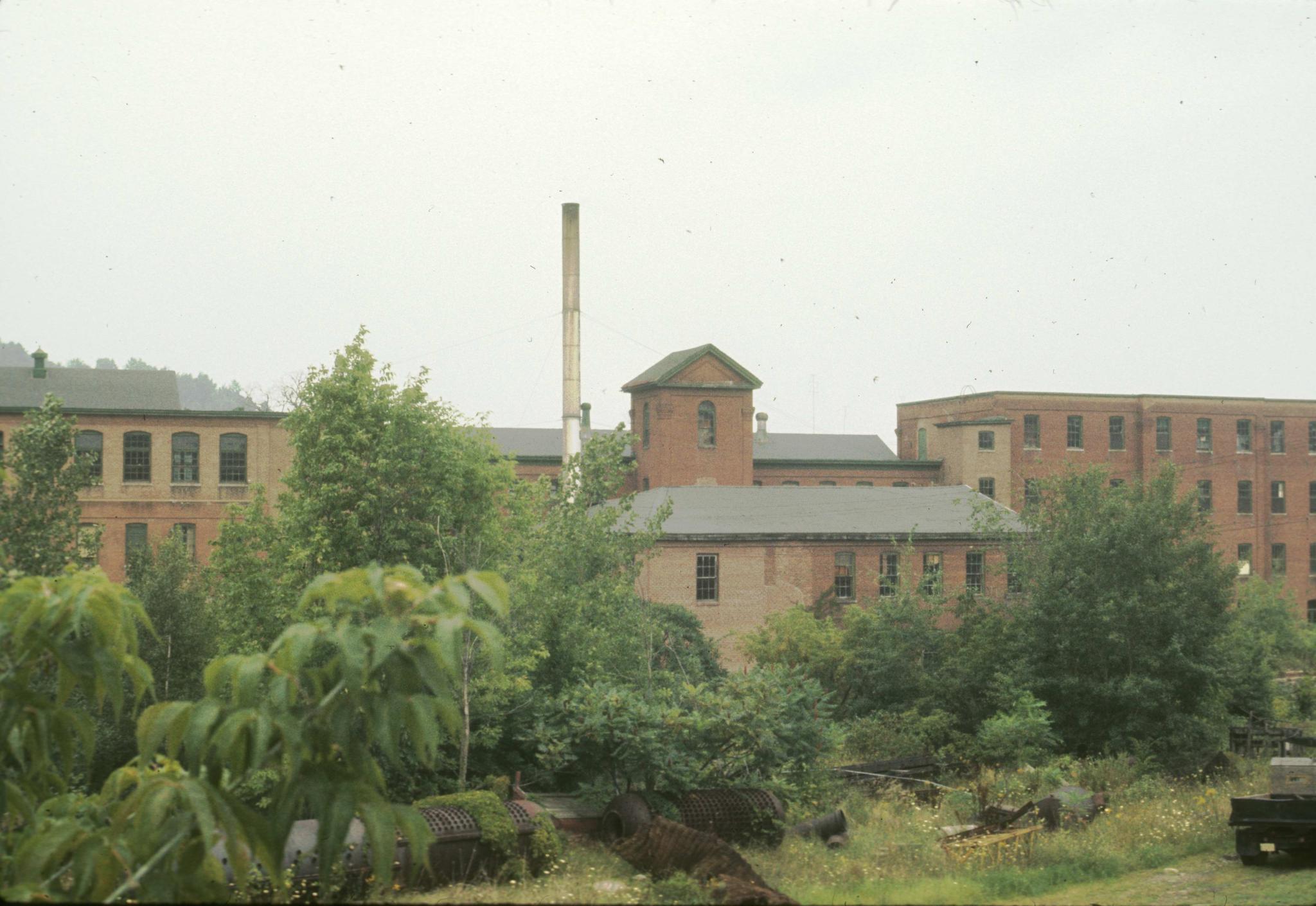 Photograph of an unidentified textile mill and tower in Glove Village,…