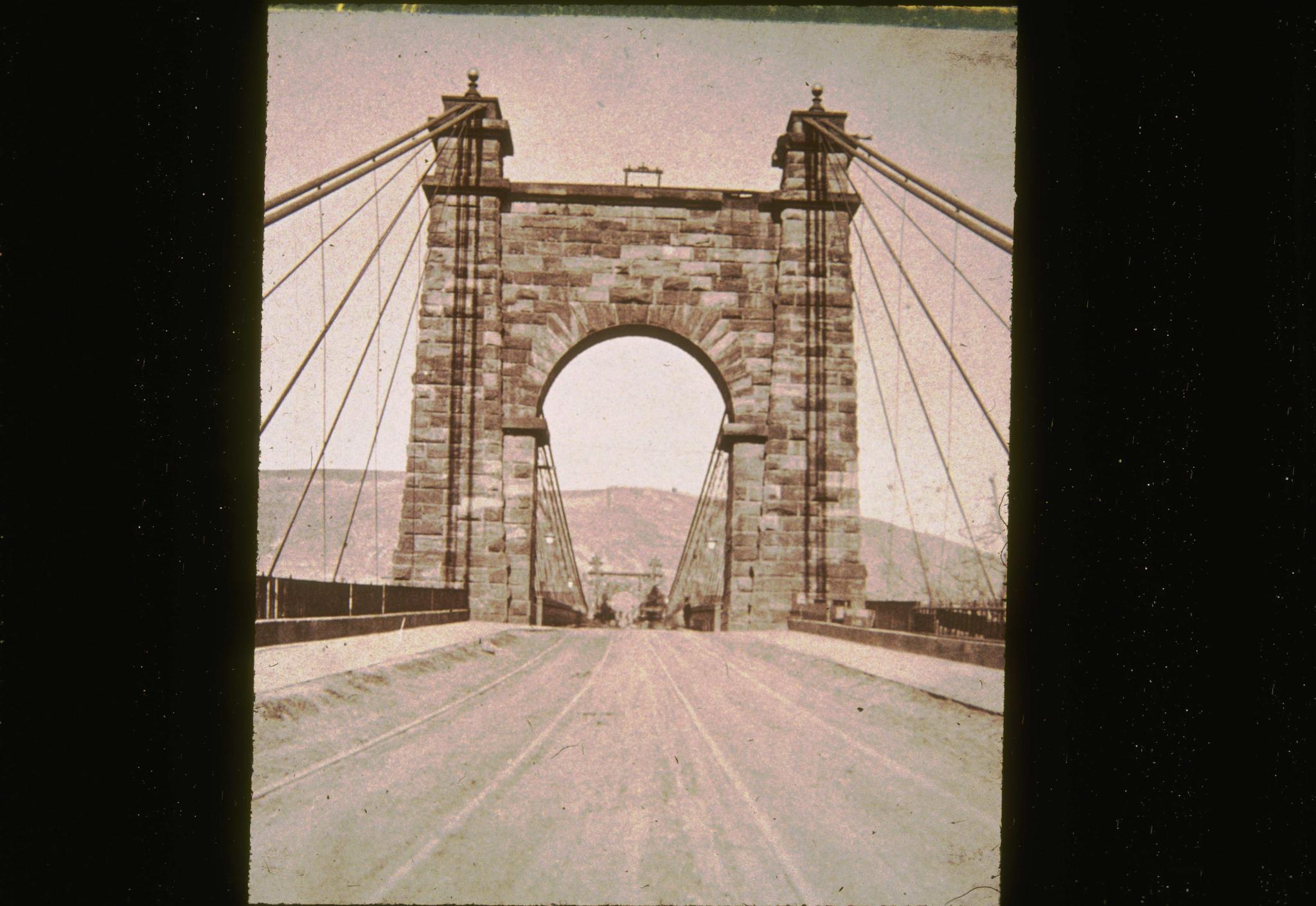 Historic photograph of the Wheeling Bridge looking along the deck.  The…