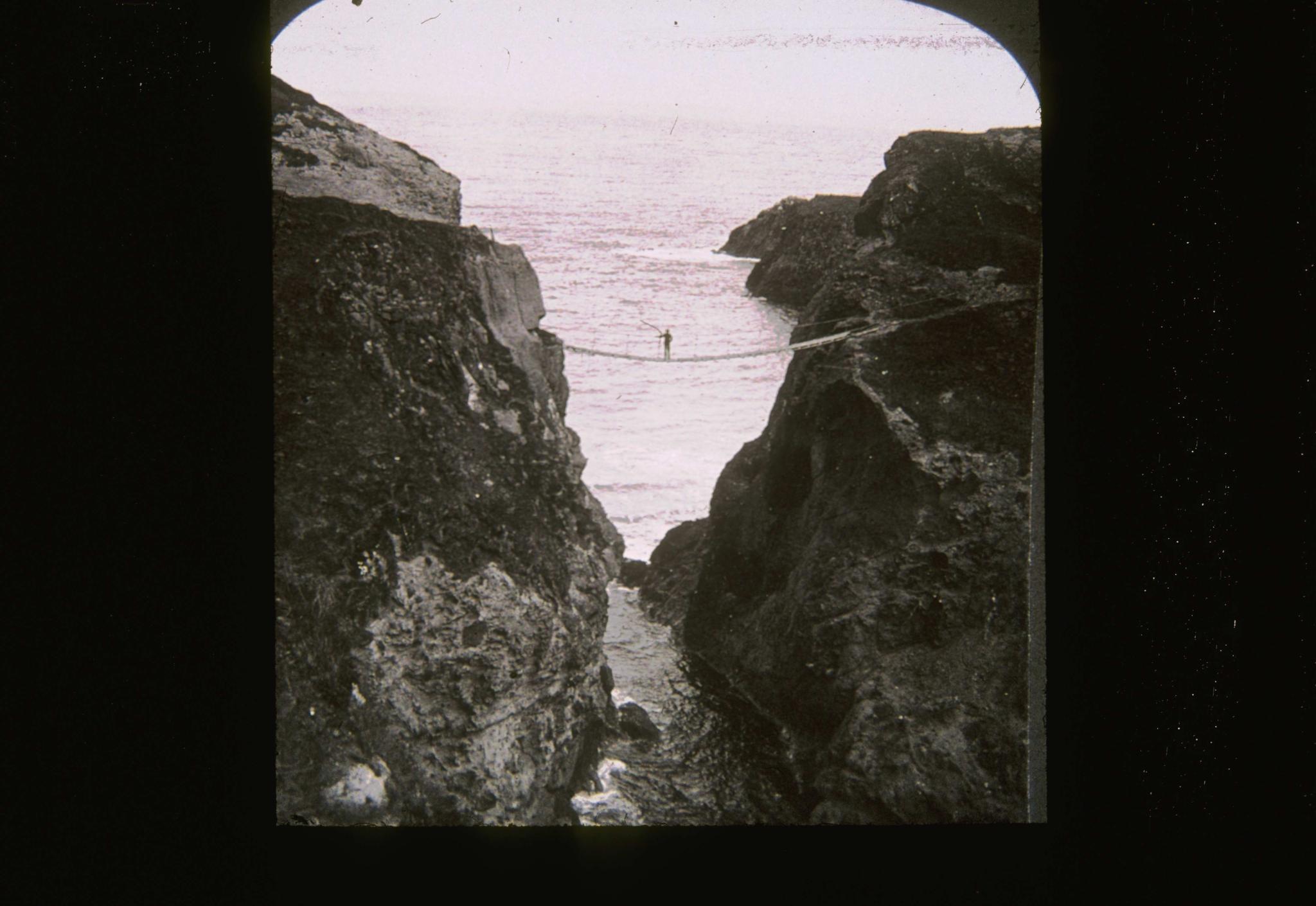 Historic photograph of an individual standing on the rope bridge.