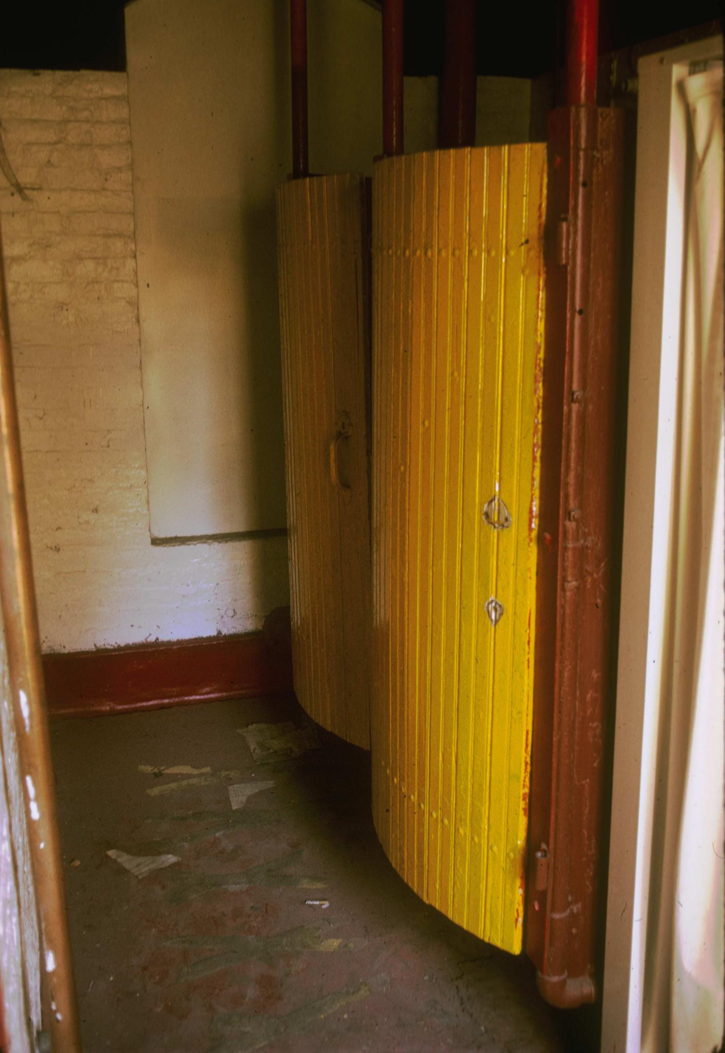 Photograph of bowed toilet stall doors in the mill.