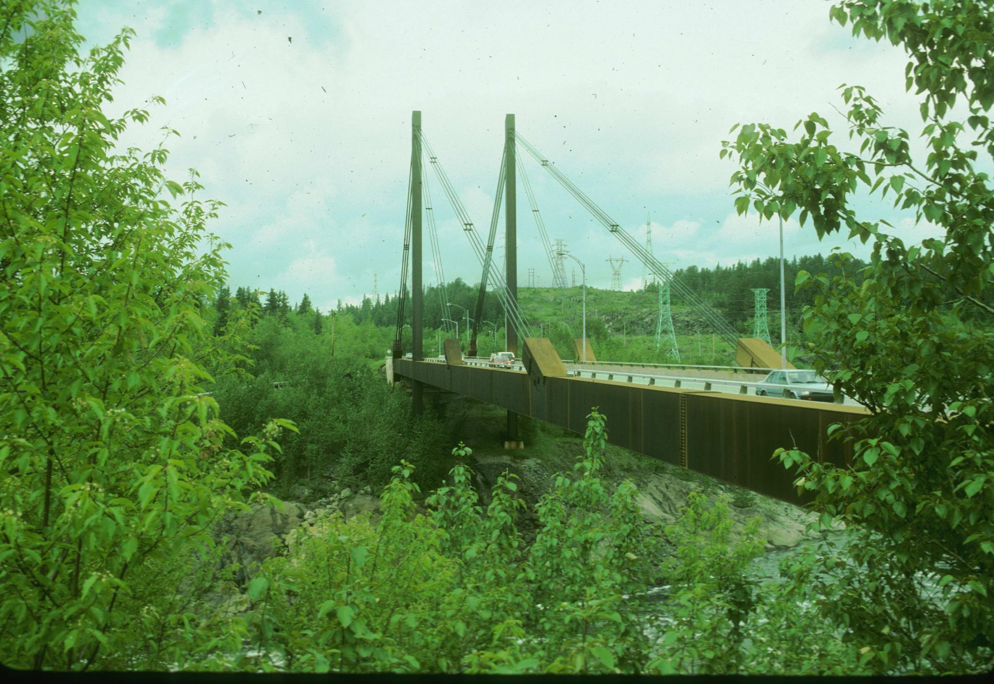 Photograph of an unidentified cable-stay bridge in Quebec. Cars are crossing…