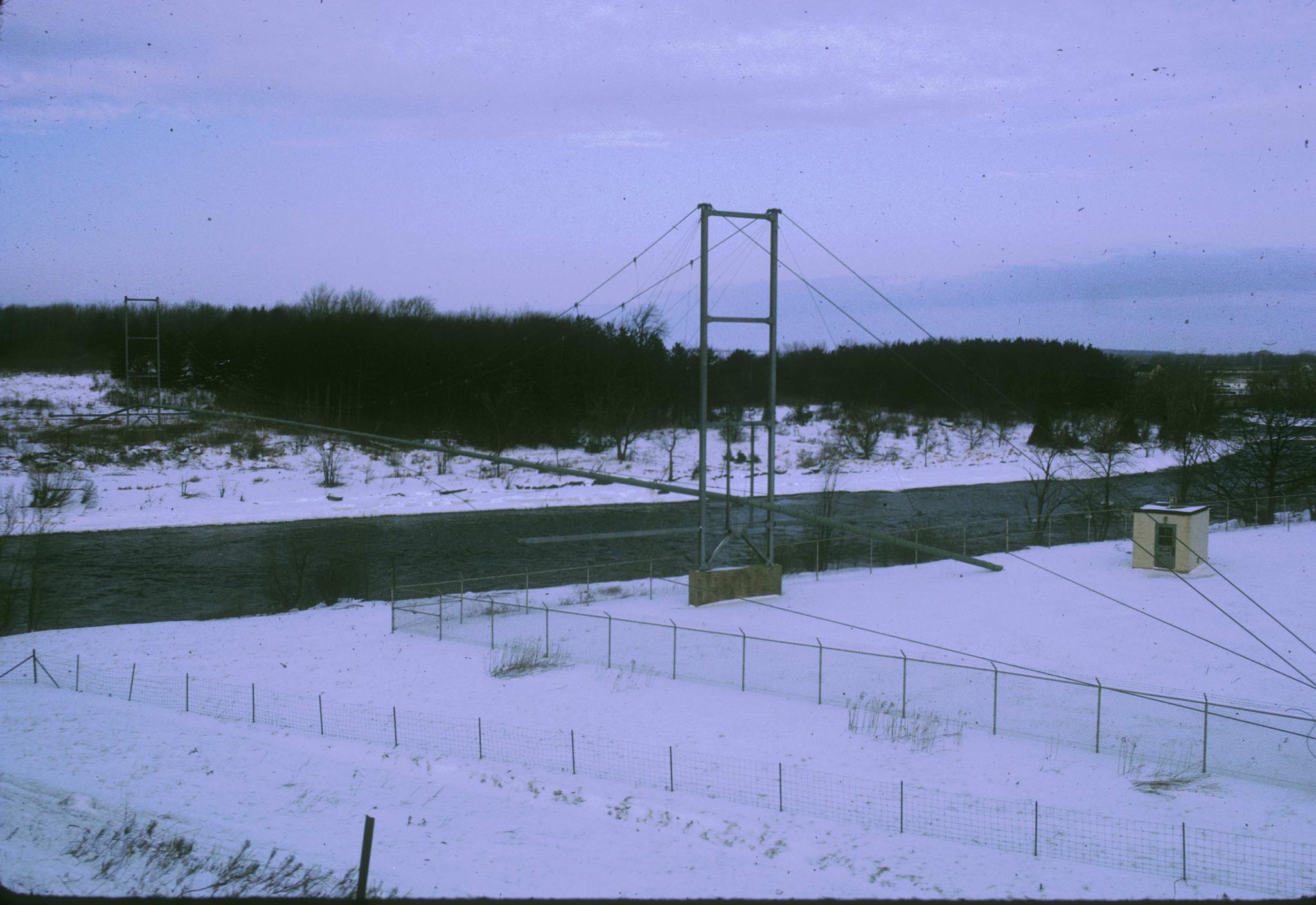 Photograph of an unidentified pipe suspension bridge crossing the Black River.