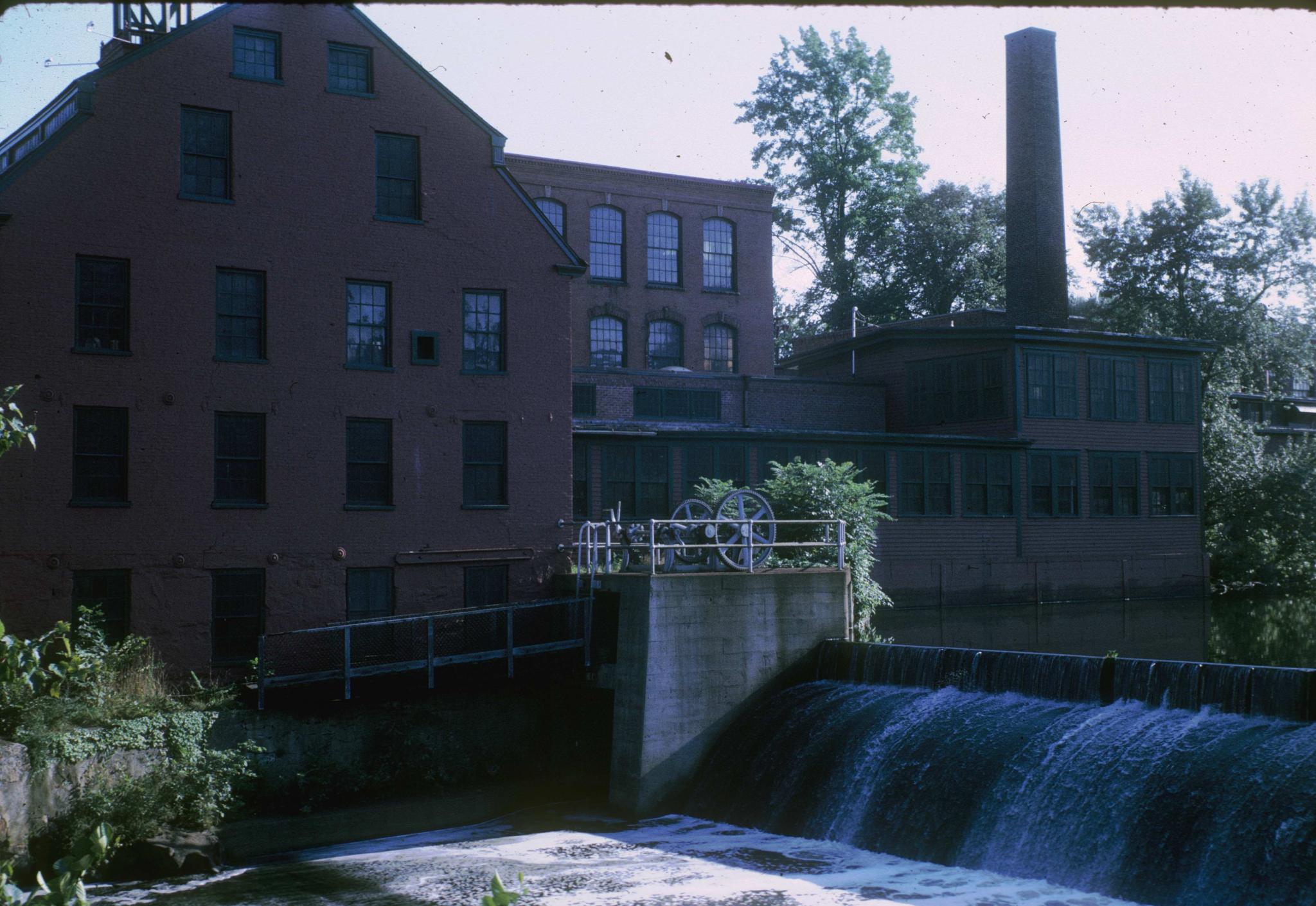 Photograph of the original brick mill building in Whitinsville, Massachusetts…