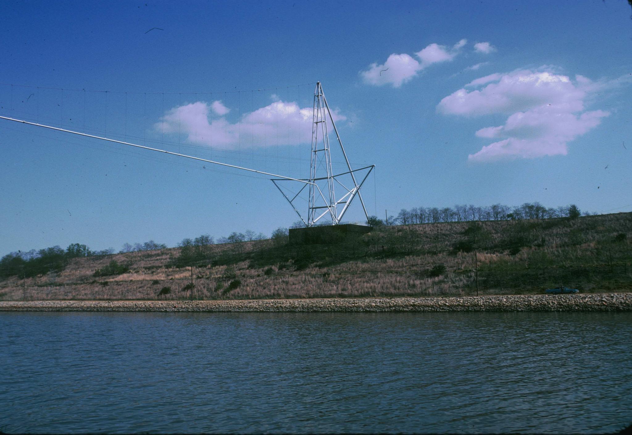 Photograph of the landing of an unidentified pipe suspension bridge spanning…