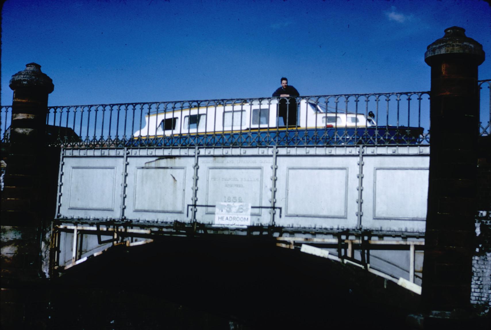 Canal boat and man crossing one of three iron aqueducts on the Stratford Canal.