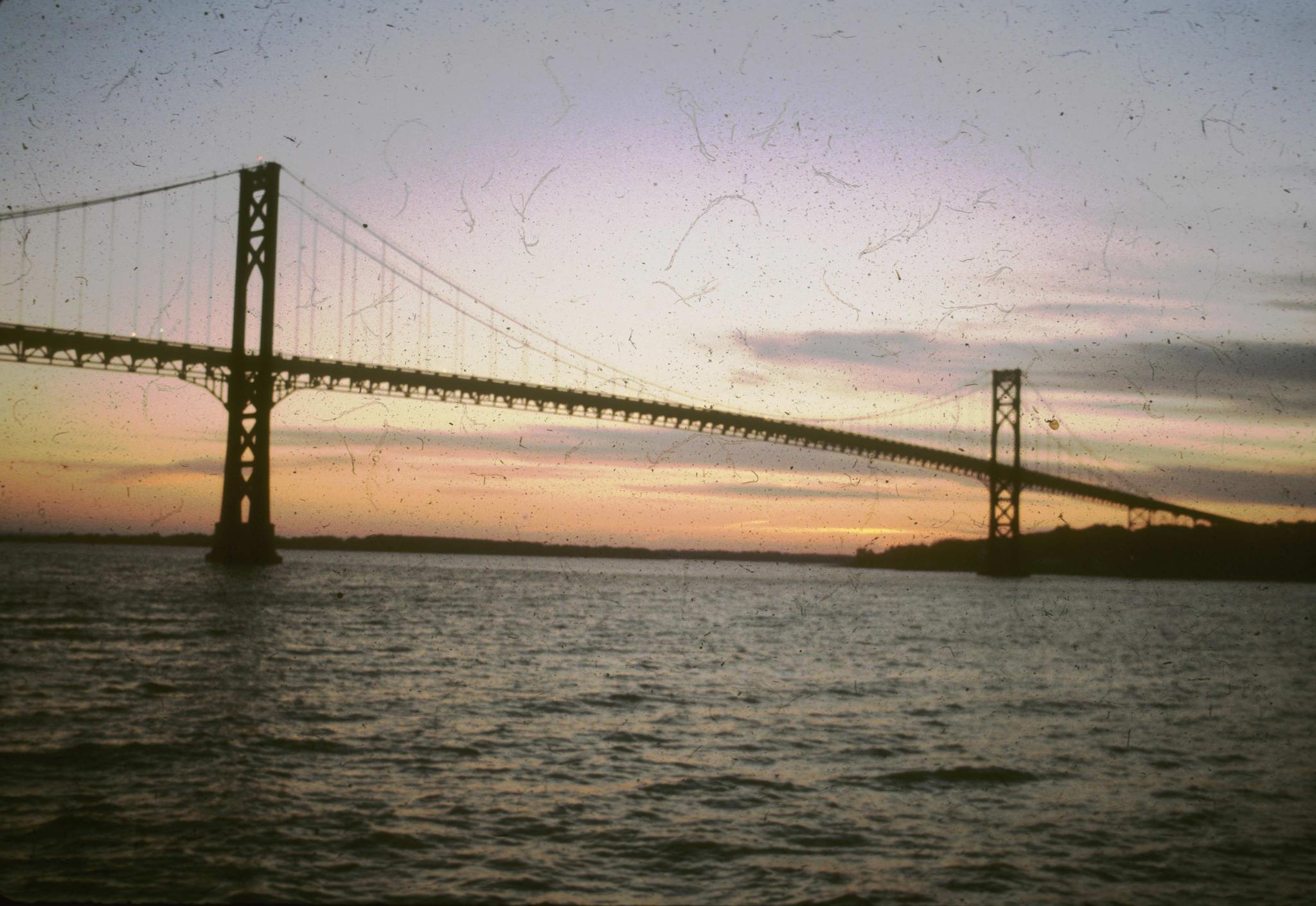 Badly damaged sunset photograph of the Mount Hope Bridge.