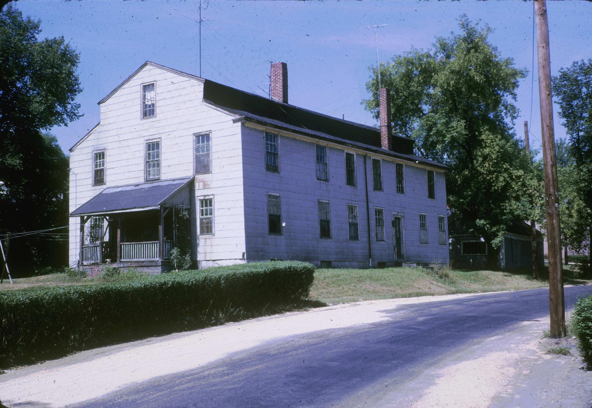 Photograph of an old frame mill (?) building on the grounds of the 1869 main…