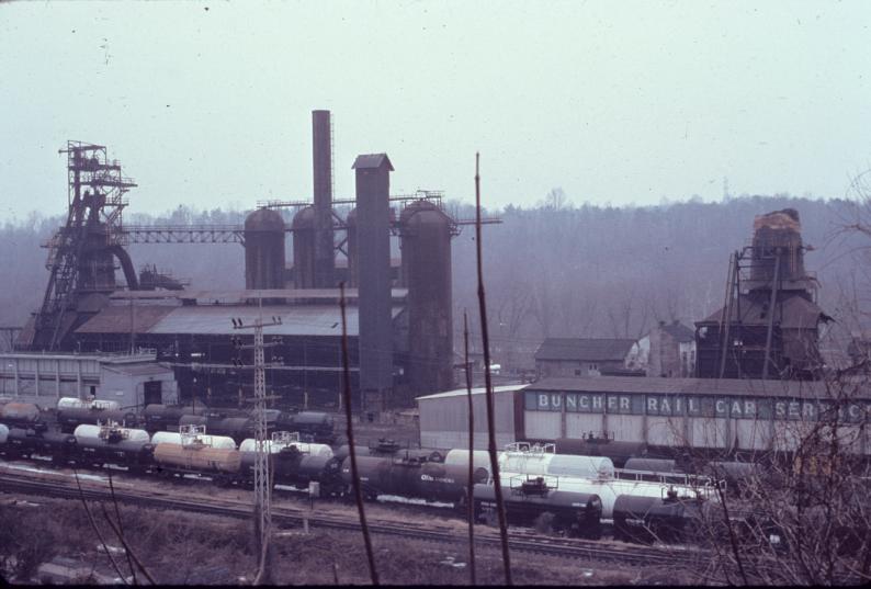 Overview of blast furnace.  Railyard in foreground with numerous tanker cars.…