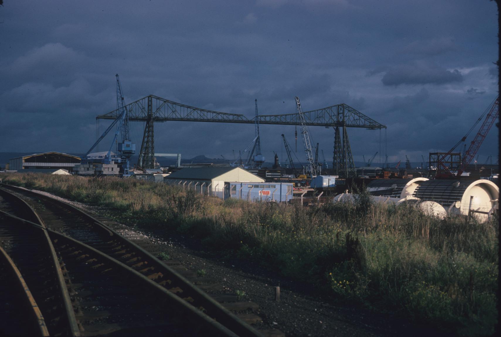 The Middlesbrough Transporter Bridge, with dockyards, cranes, and a rail line…