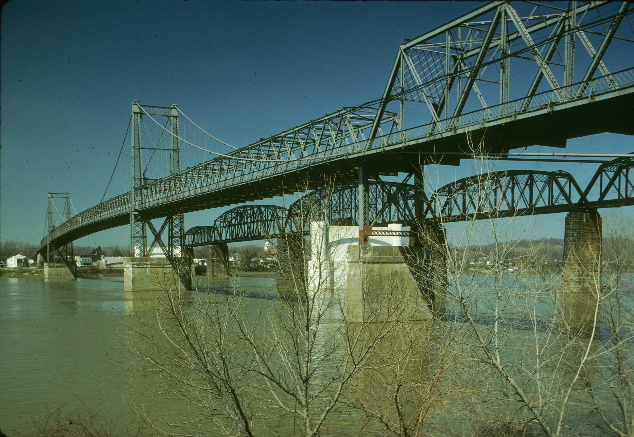 Photograph of the old Parkersburg Suspension bridge.  A steel arch railroad…