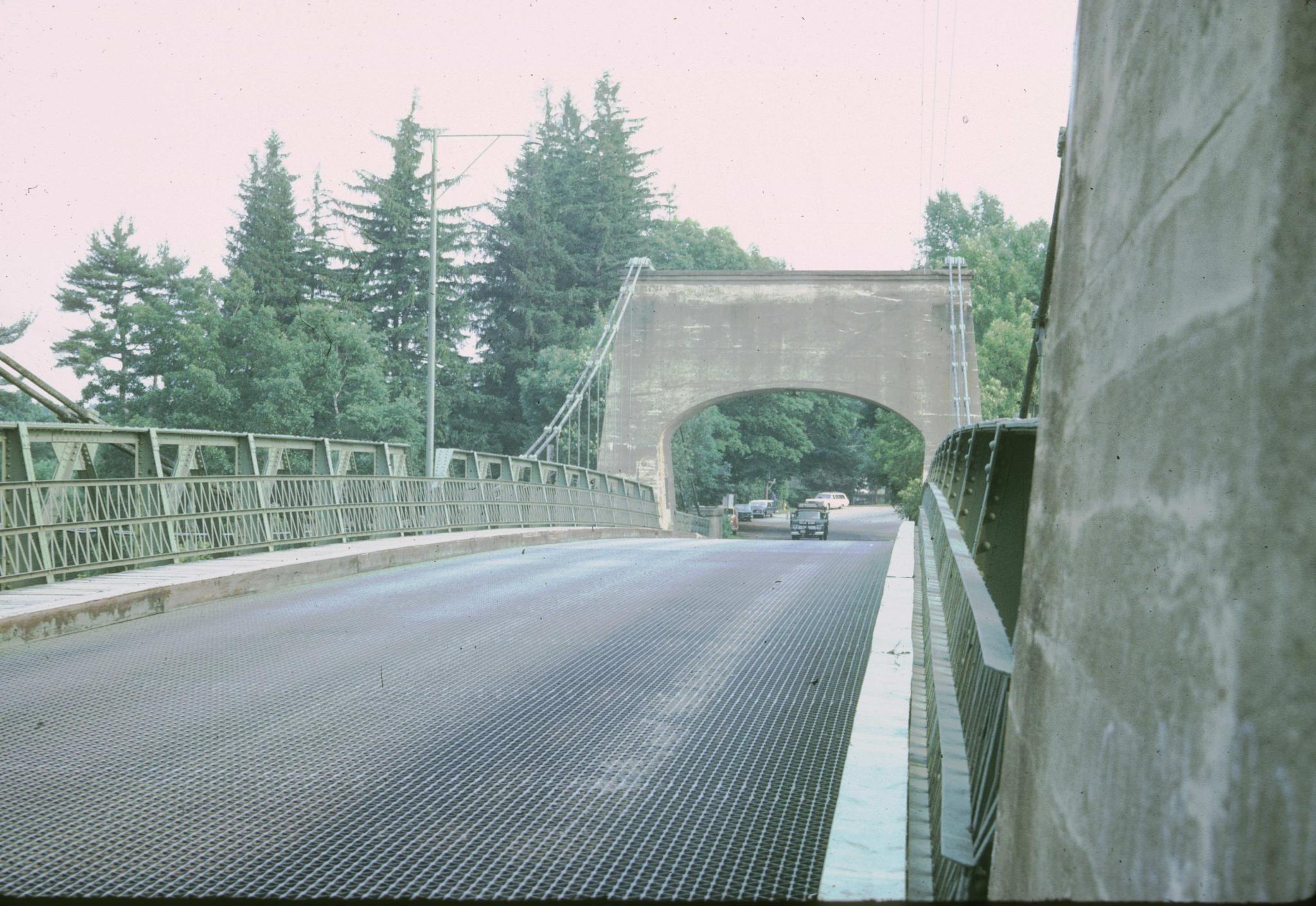 Photograph down the deck of the Newburyport bridge.  Several vehicles are…