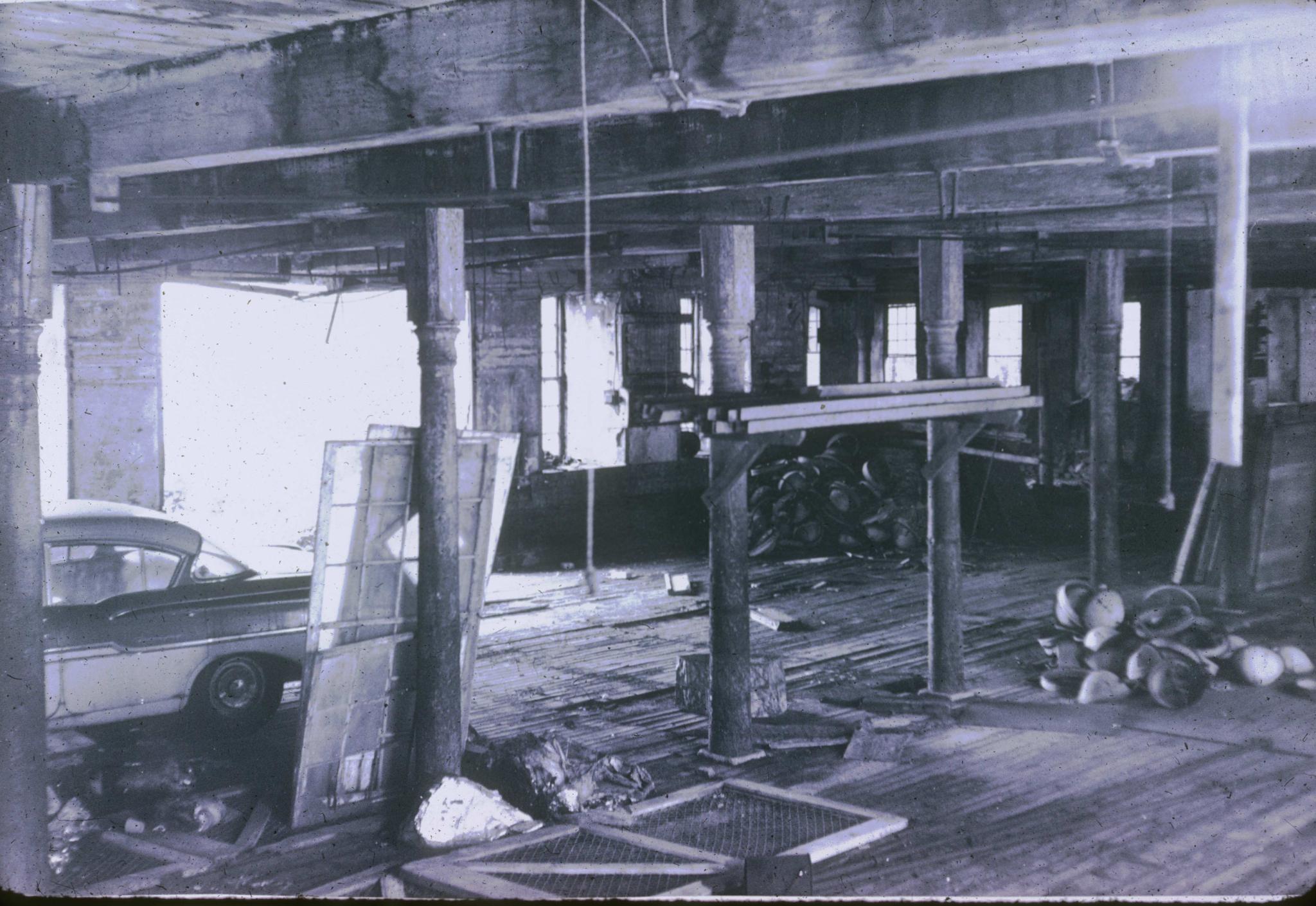 Black and white photograph of the interior of an unidentified mill in…