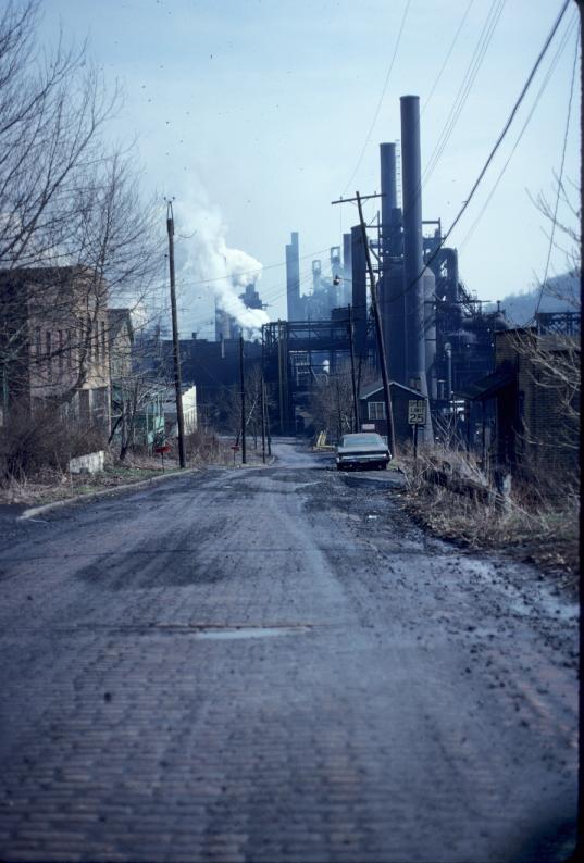 Photograph down brick street to Weirton mill.  Residential buildings on right…