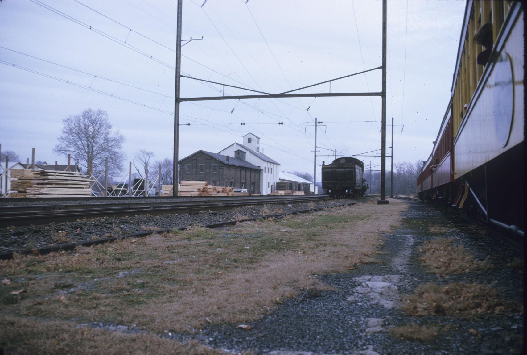 View of engine (tender) passing passenger cars on siding