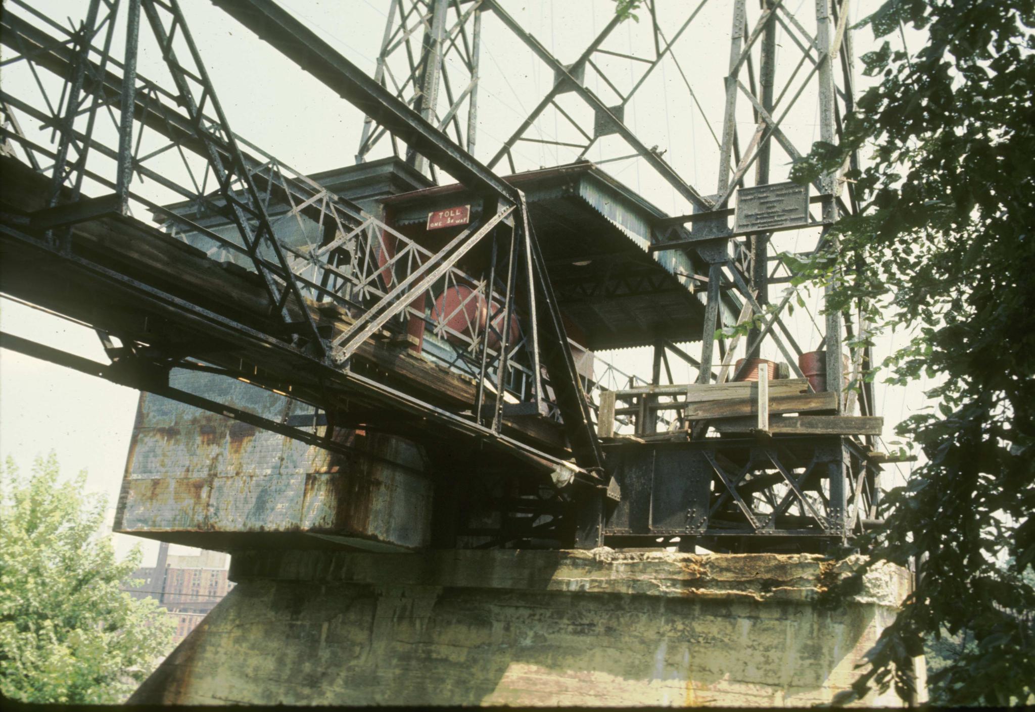 Photograph of the toll-house and a support tower of the Ticonic foot bridge…