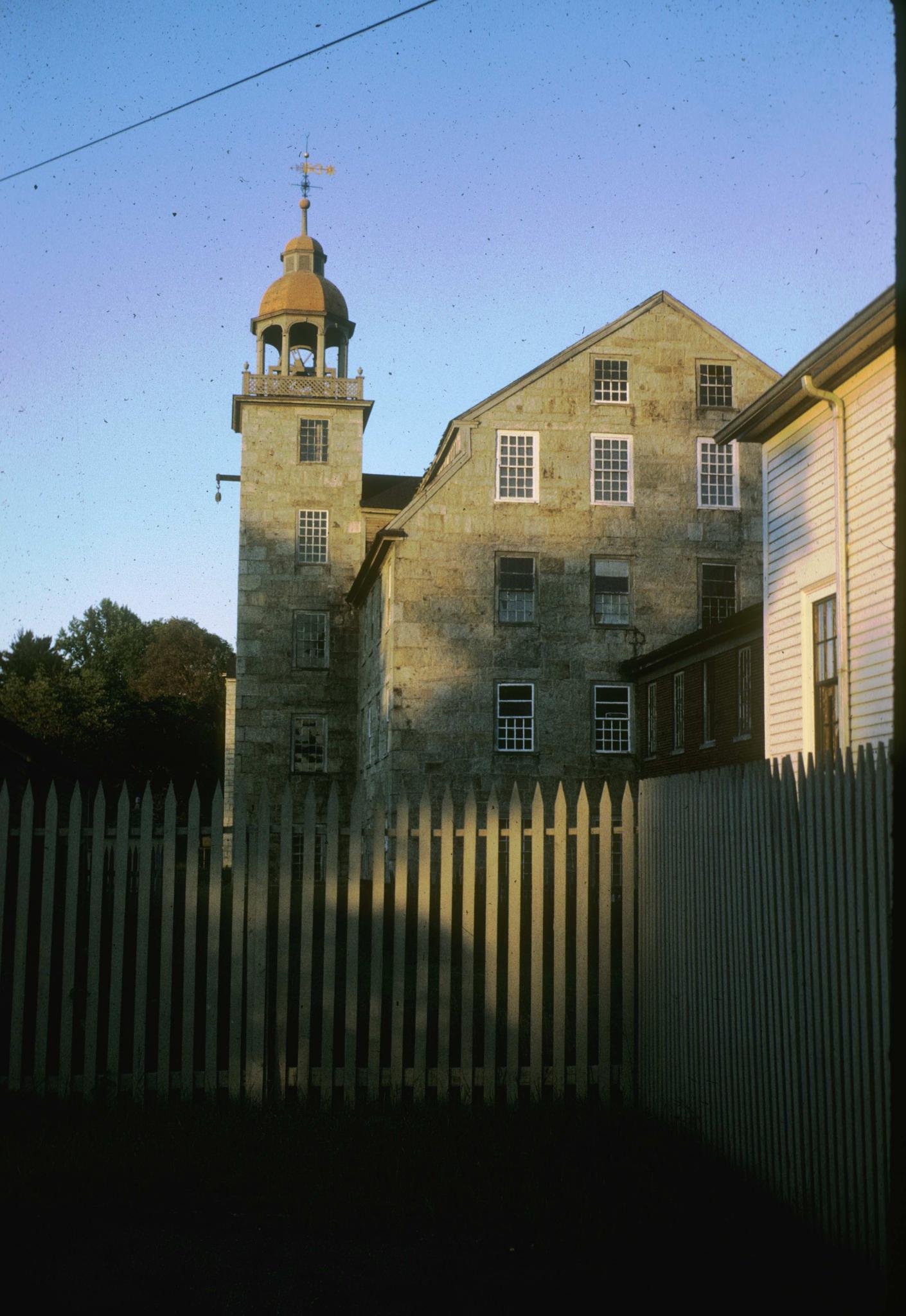 Photograph of the mill taken from behind a picket fence.