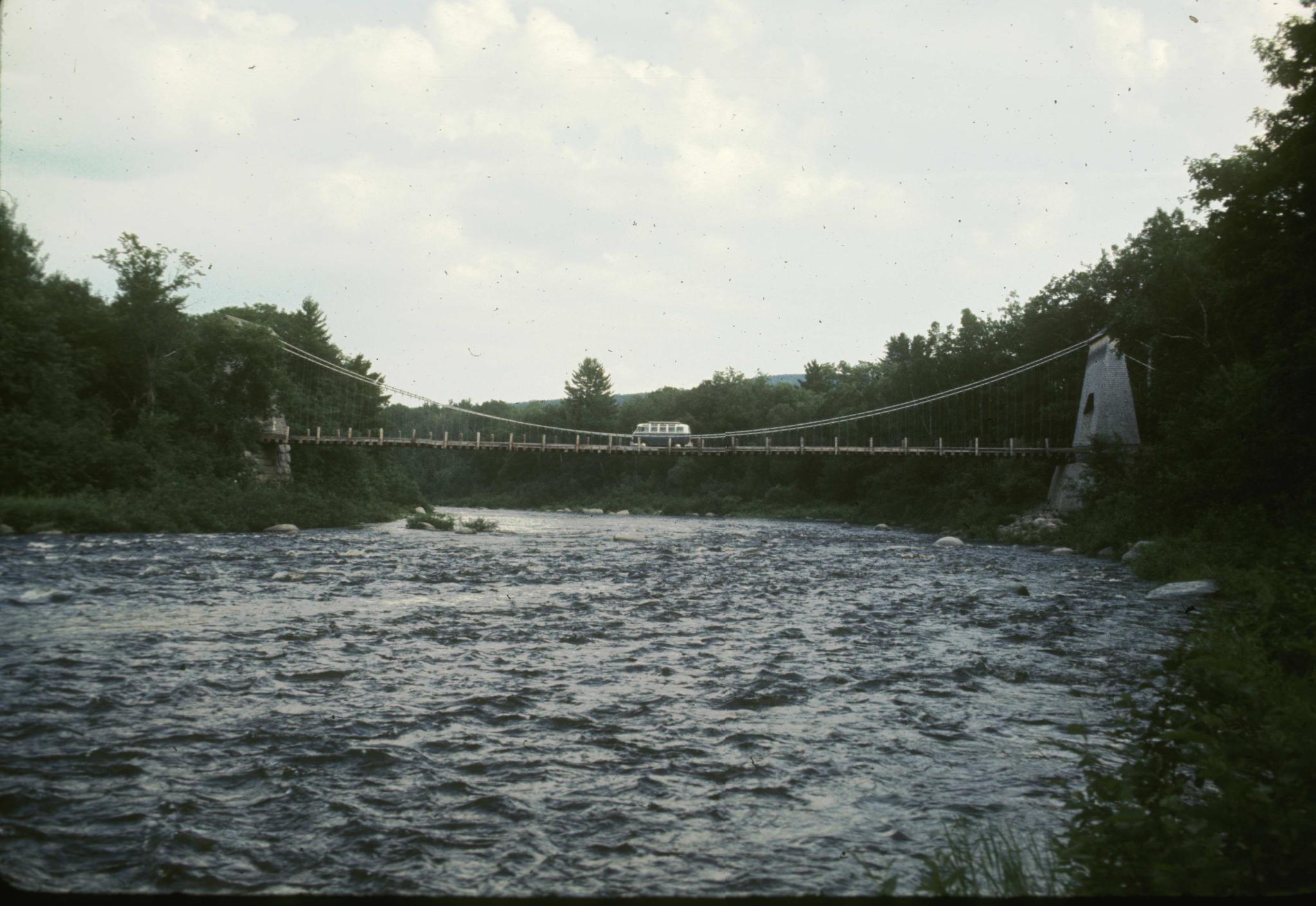 Side view of the wire bridge at New Portland taken from the river.  There is a…