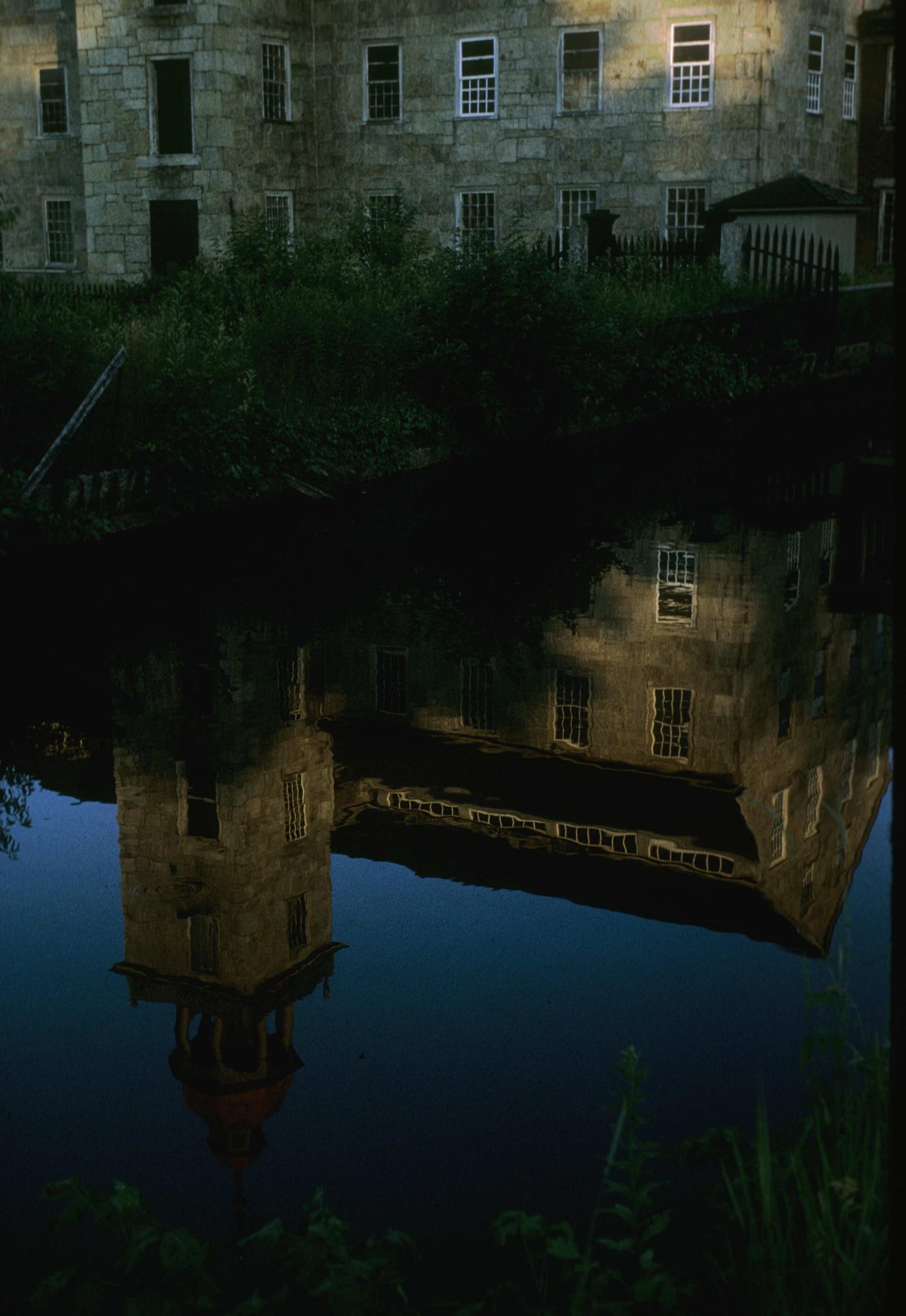 Photograph of the reflection of the mill in a canal.