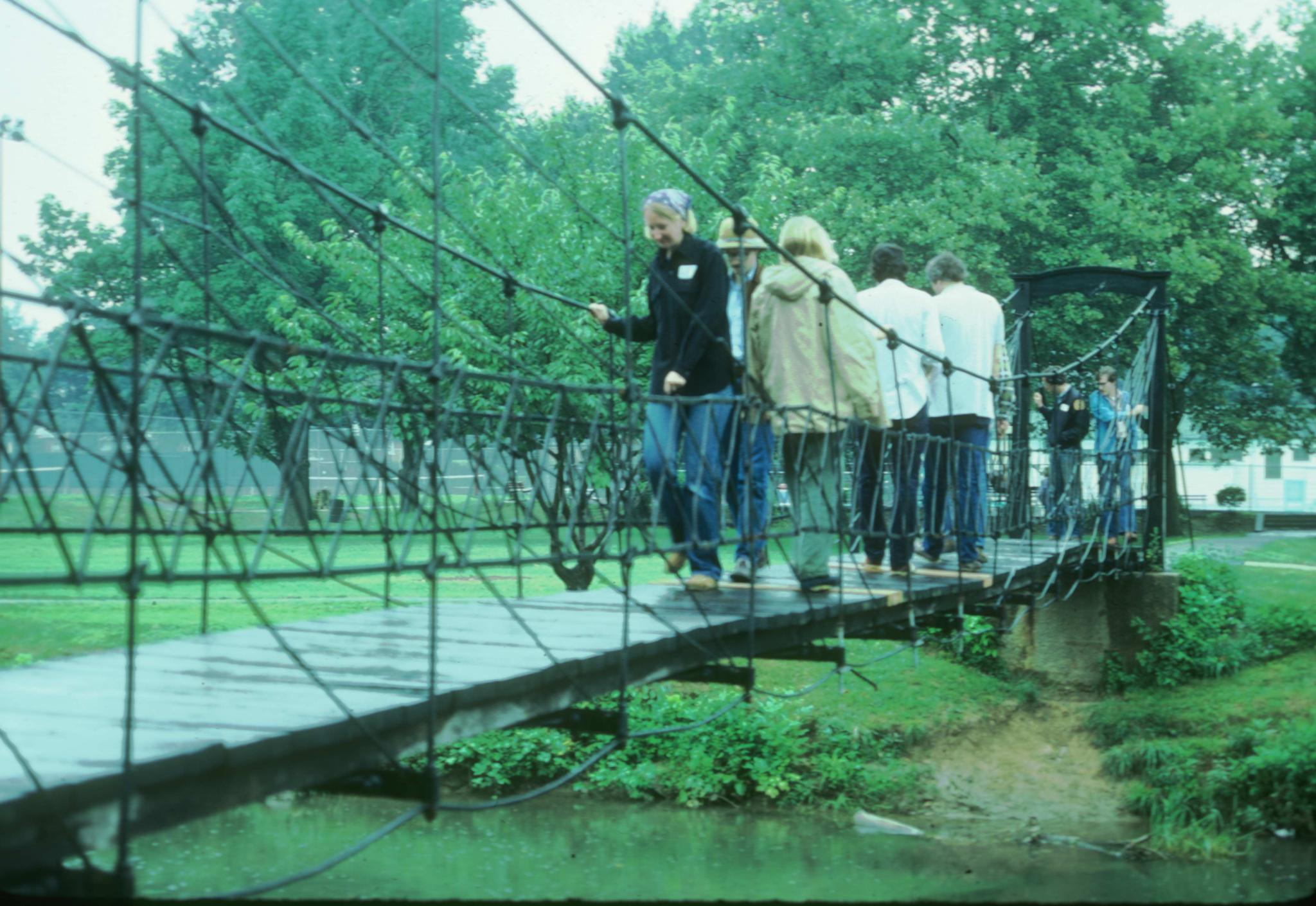 Photograph of several people crossing the bridge at the MCMOC field strip in…