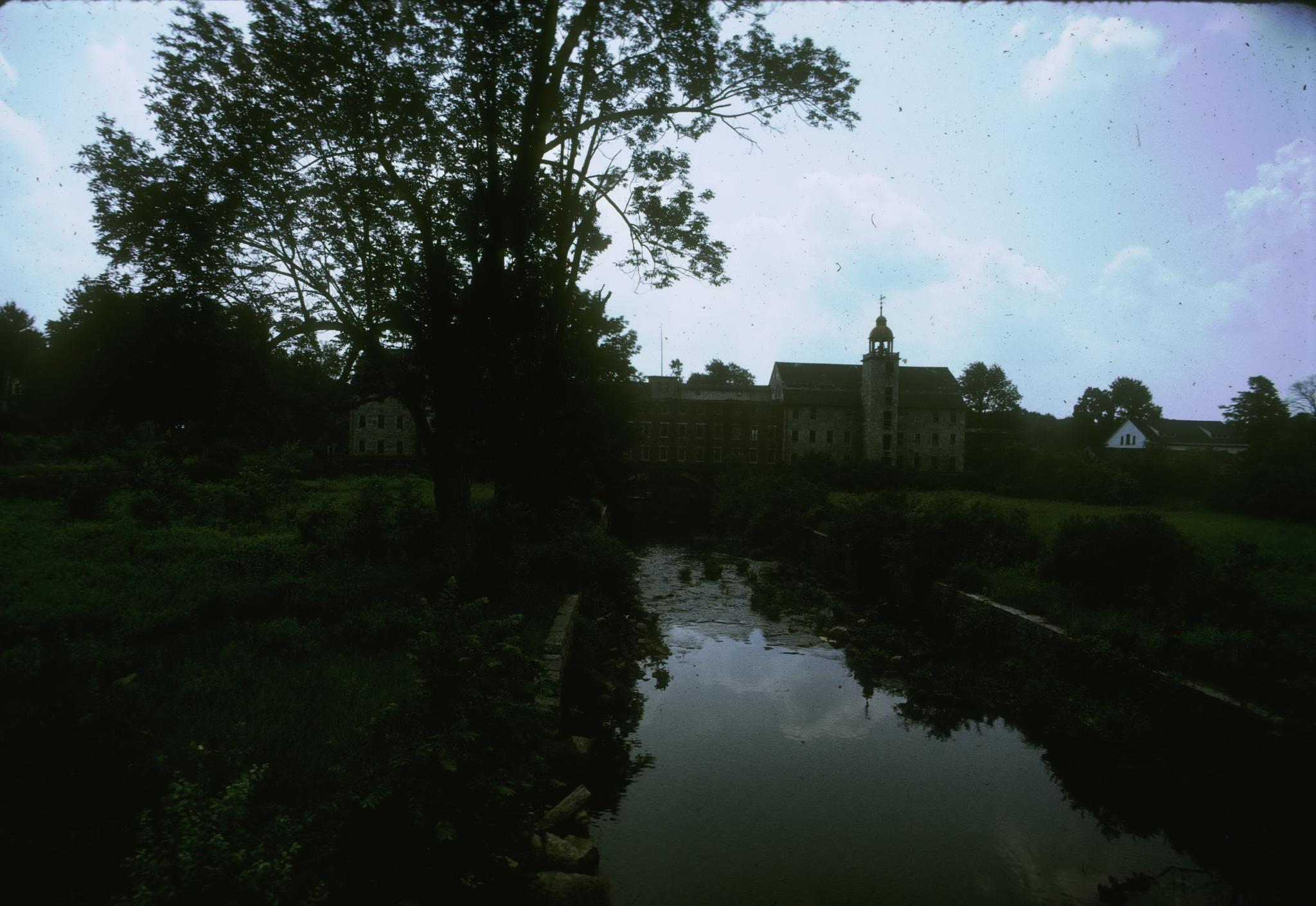 Photograph of the mills taken from the bank of the Mumford River.  Photograph…