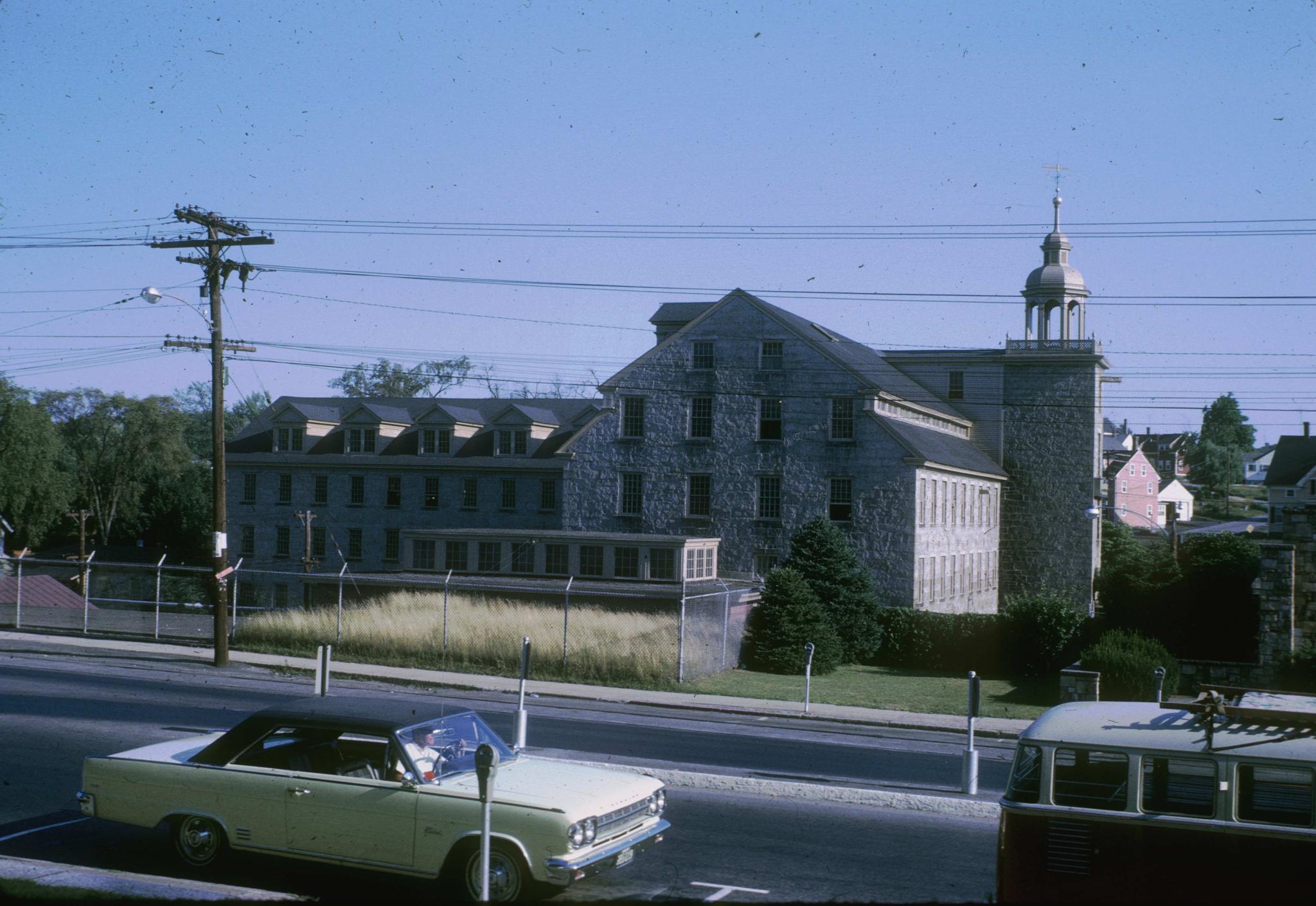 Photograph of the stone mill (The Shop) in Whitinsville, Massachusetts.  A…