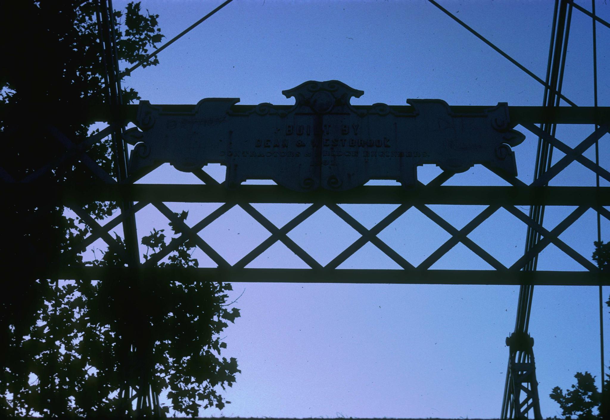 Close-up of the name and date plate on the bridge.  Photograph is dark and…